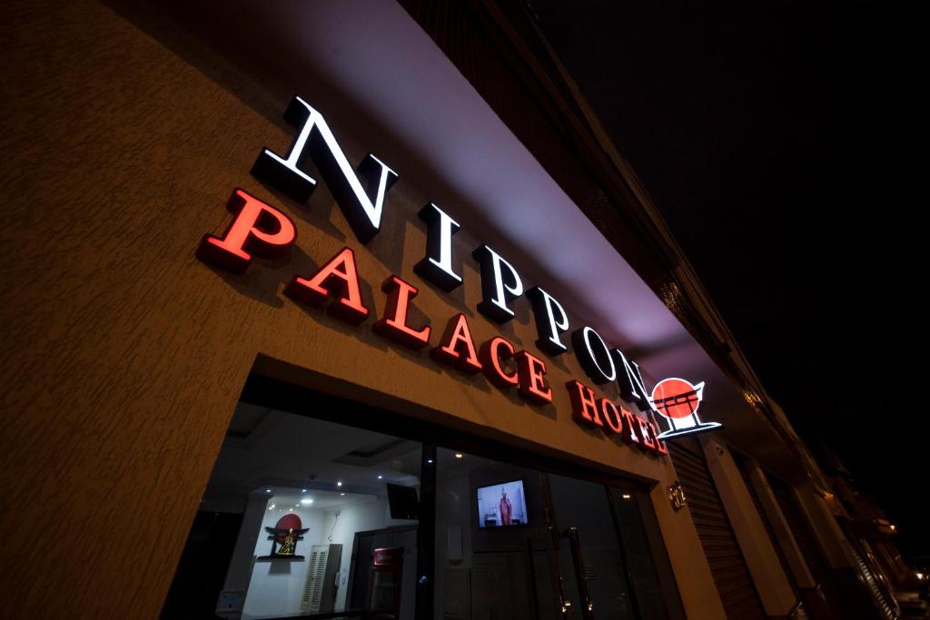 a neon sign on the front of a large store at Nippon Palace Hotel in Aparecida