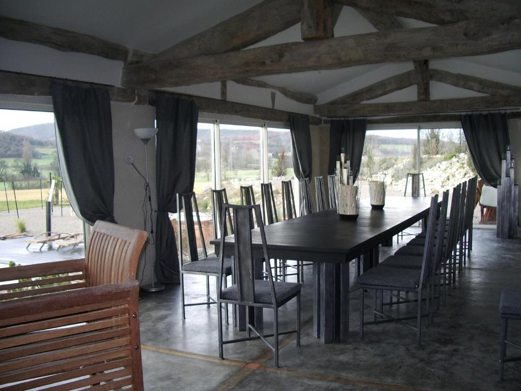 a dining room with a black table and chairs at Le Prieuré des Sources in La Répara