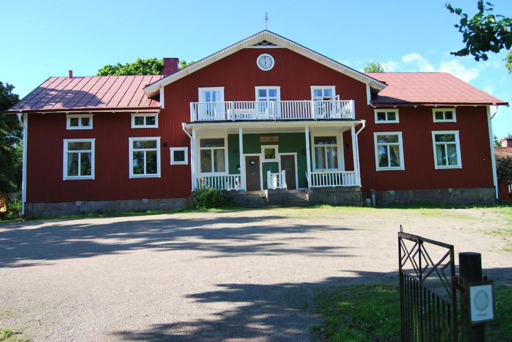 une maison rouge avec un toit rouge et une allée dans l'établissement Rytterne Kyrkskola, à Sorby