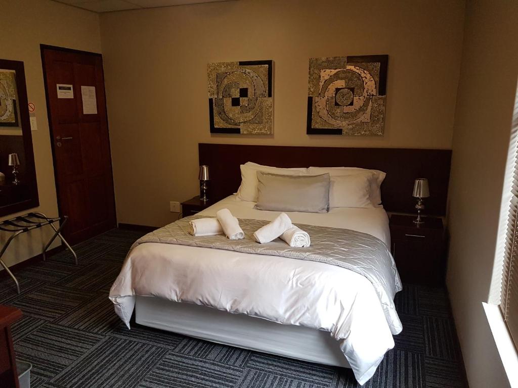 a bedroom with a bed with two towels on it at A Contempo Guesthouse in Bloemfontein