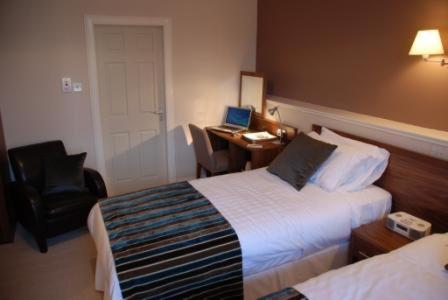 a hotel room with two beds and a desk with a laptop at Kirklands Hotel in Kinross