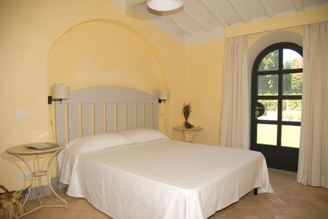 a bedroom with a white bed and a window at Fonte del Lupo in Porto Ercole