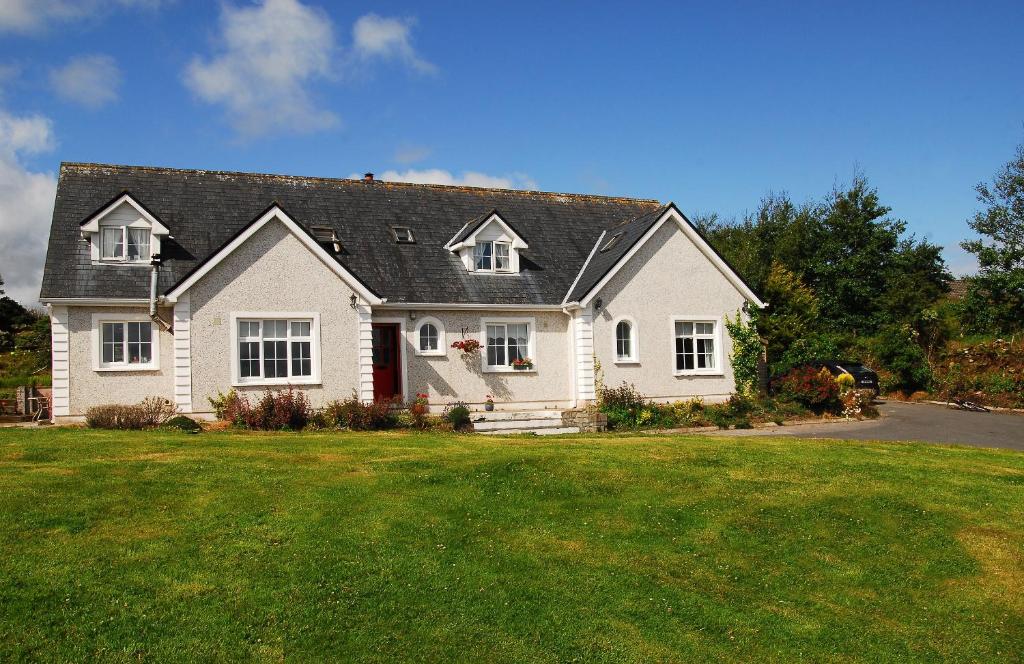 une maison blanche avec un toit noir et une cour dans l'établissement Nephin Lodge, à Westport