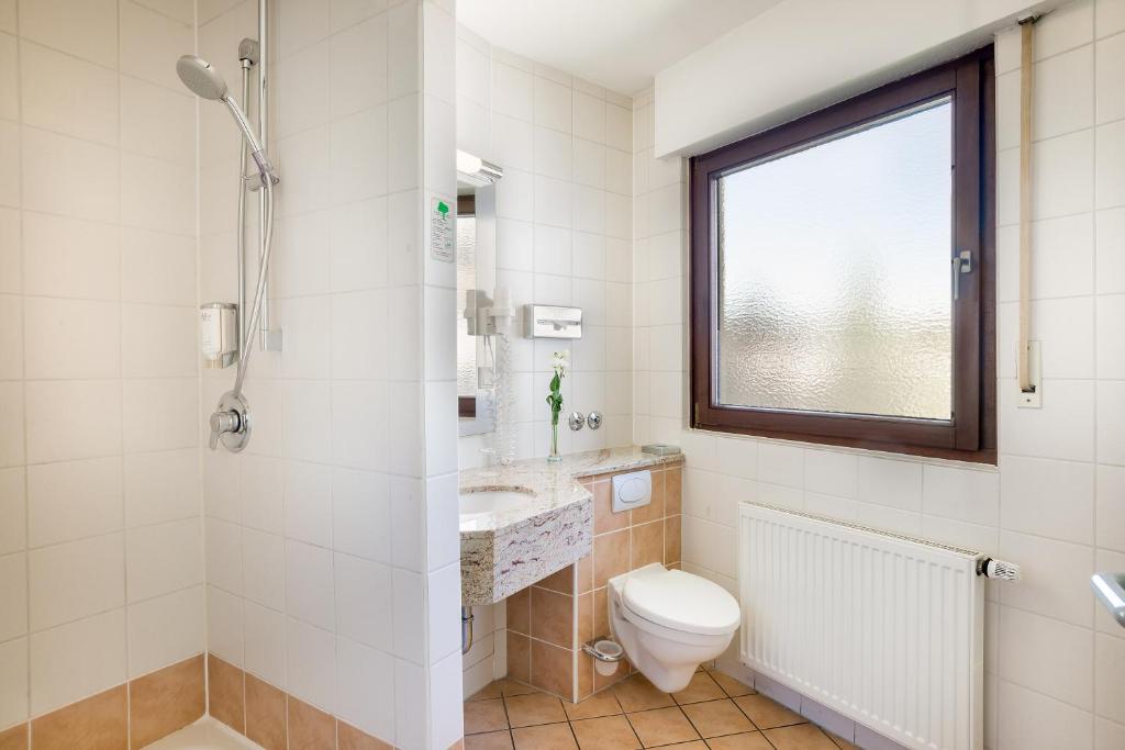 a bathroom with a toilet and a sink at Hotel Rega Stuttgart in Stuttgart