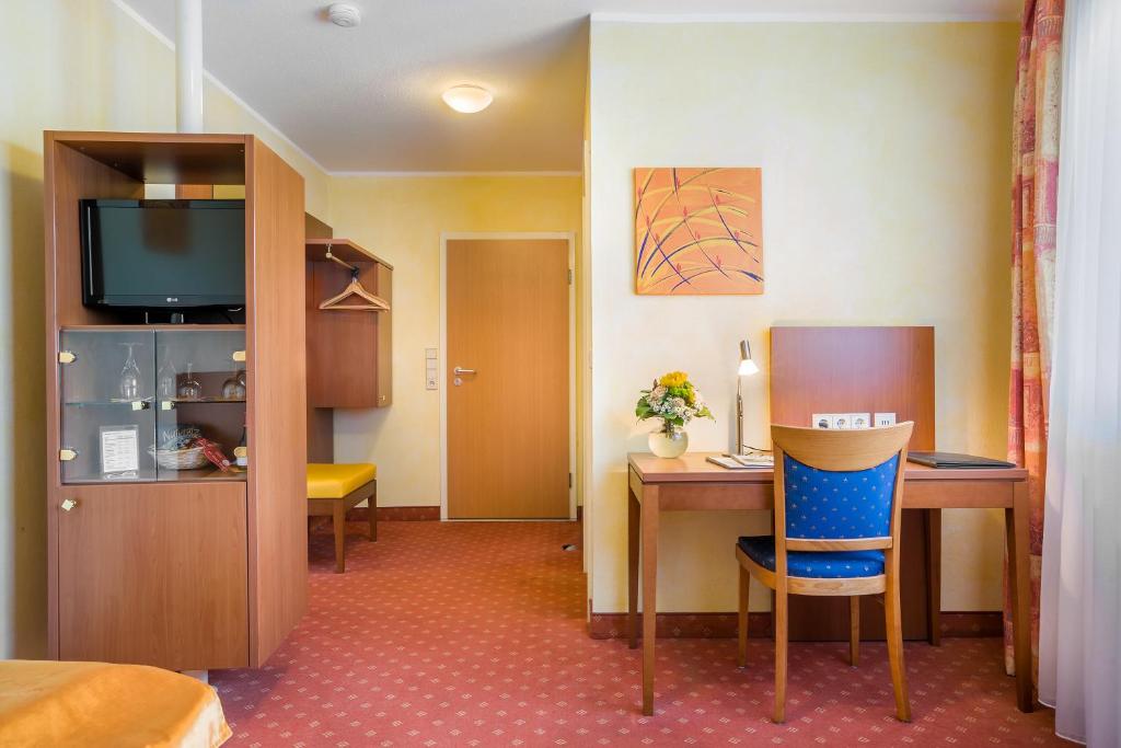 a hotel room with a desk and a television at Hotel Rega Stuttgart in Stuttgart