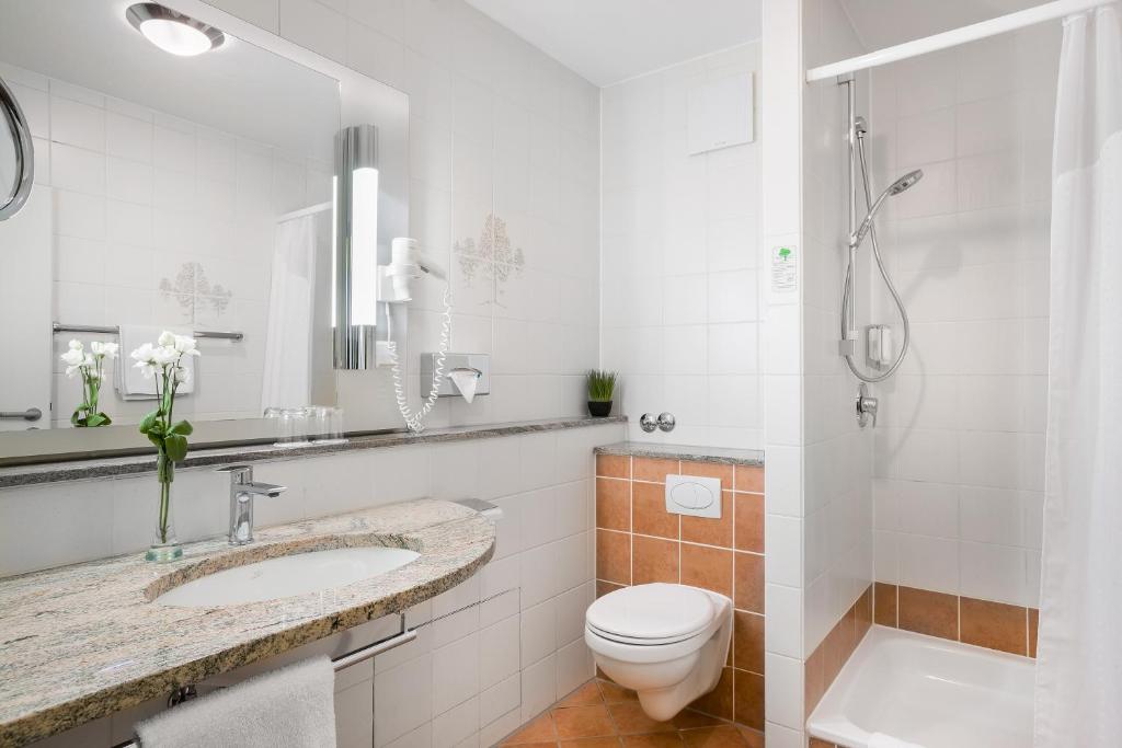 a bathroom with a toilet and a sink and a shower at Hotel Rega Stuttgart in Stuttgart