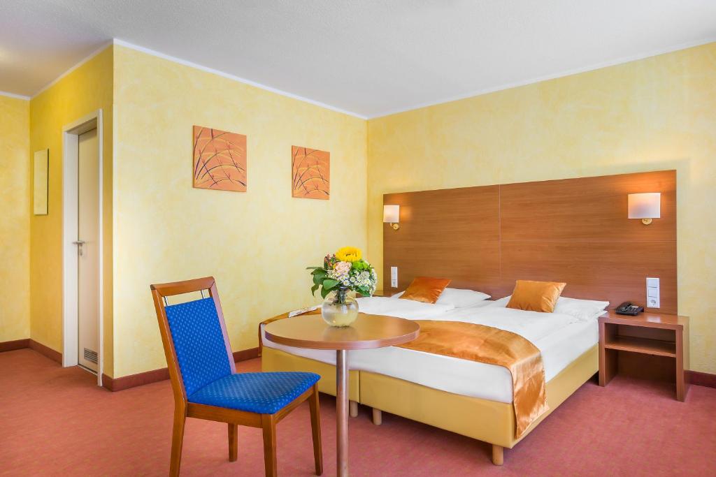 a hotel room with a bed and a table and chair at Hotel Rega Stuttgart in Stuttgart