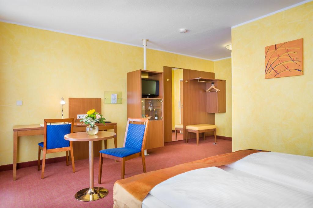 a hotel room with a bed and a table and chairs at Hotel Rega Stuttgart in Stuttgart