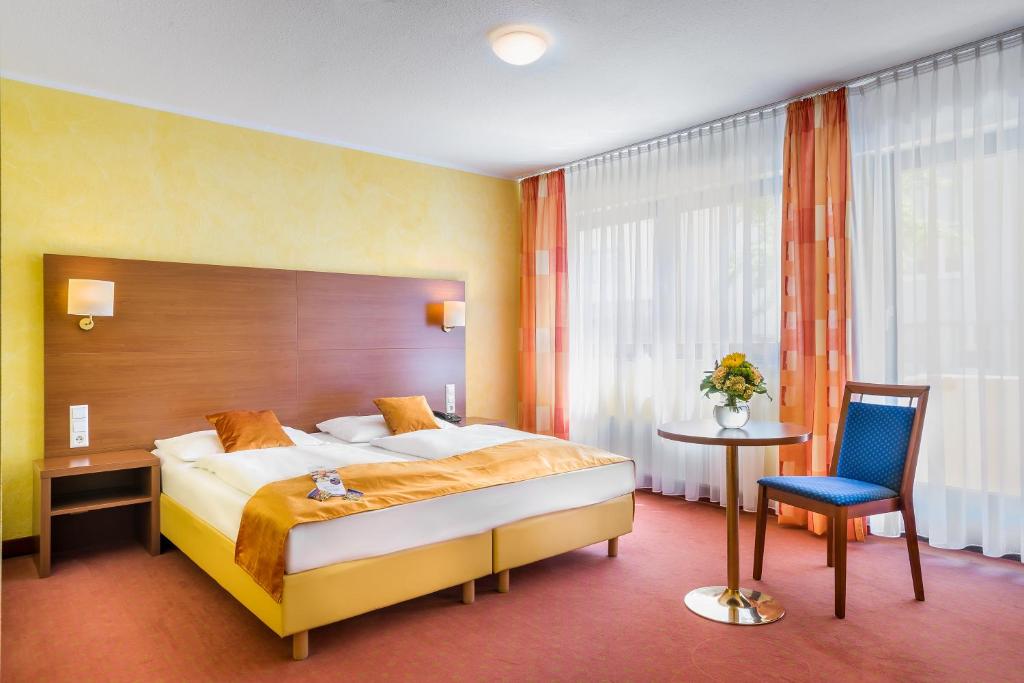 シュトゥットガルトにあるノヴム ホテル レガ シュトゥットガルトのベッド、テーブル、椅子が備わるホテルルームです。