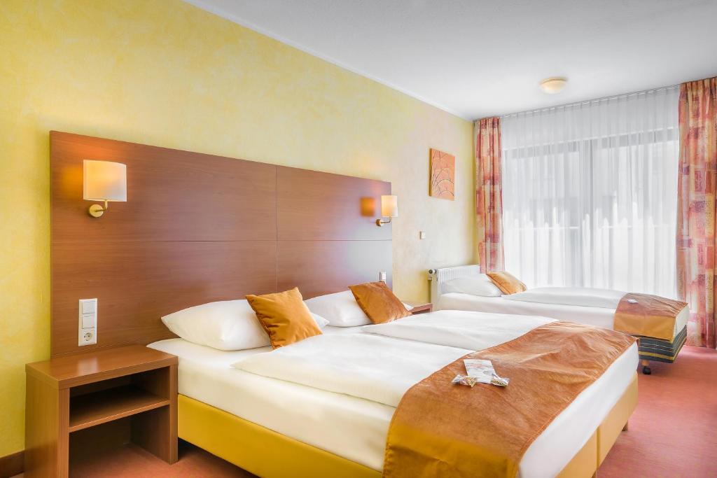 a hotel room with two beds and a window at Hotel Rega Stuttgart in Stuttgart