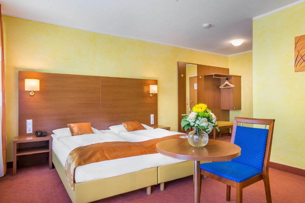 a hotel room with a large bed and a table at Hotel Rega Stuttgart in Stuttgart