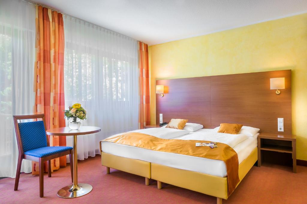 a hotel room with a large bed and a table at Hotel Rega Stuttgart in Stuttgart