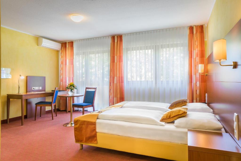 a bedroom with a large bed and a desk at Hotel Rega Stuttgart in Stuttgart