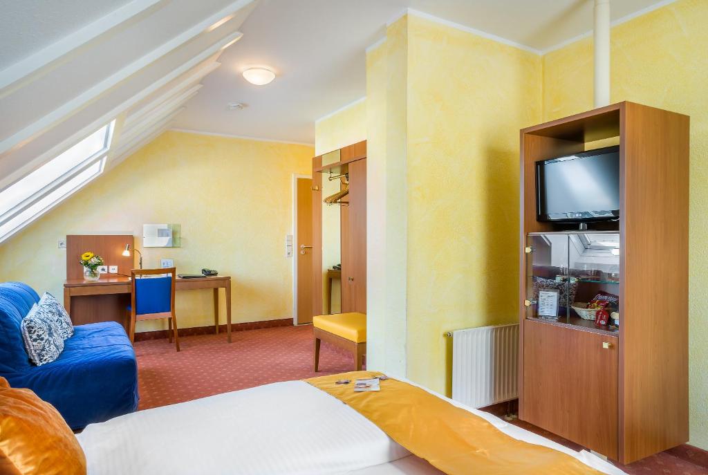 a hotel room with a bed and a tv at Hotel Rega Stuttgart in Stuttgart