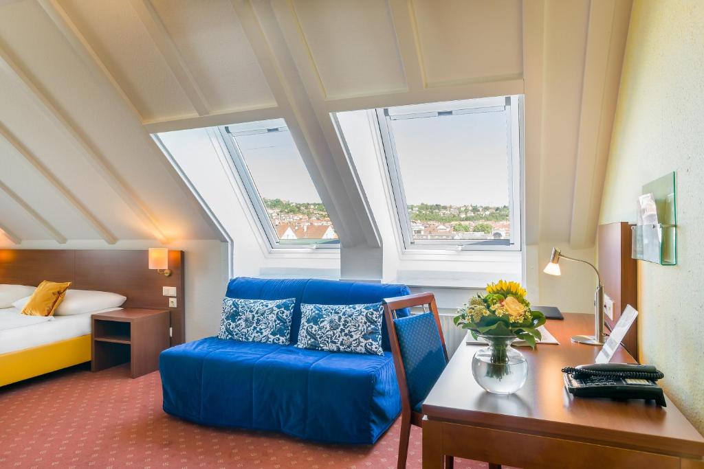 a hotel room with a blue couch and a desk at Hotel Rega Stuttgart in Stuttgart