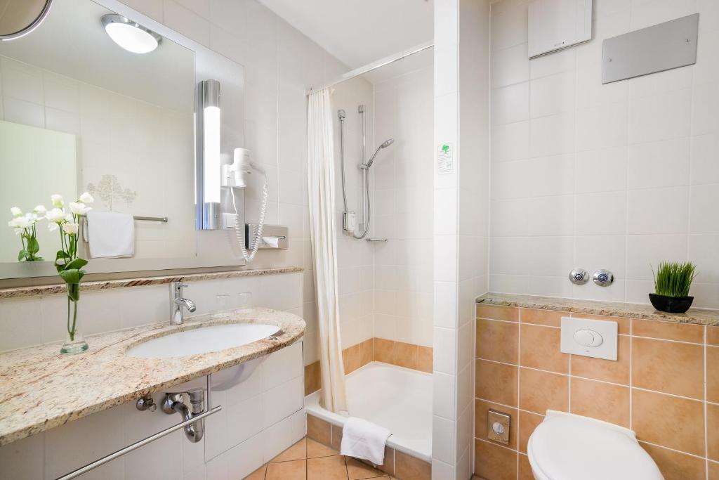 a bathroom with a sink and a shower and a toilet at Hotel Rega Stuttgart in Stuttgart