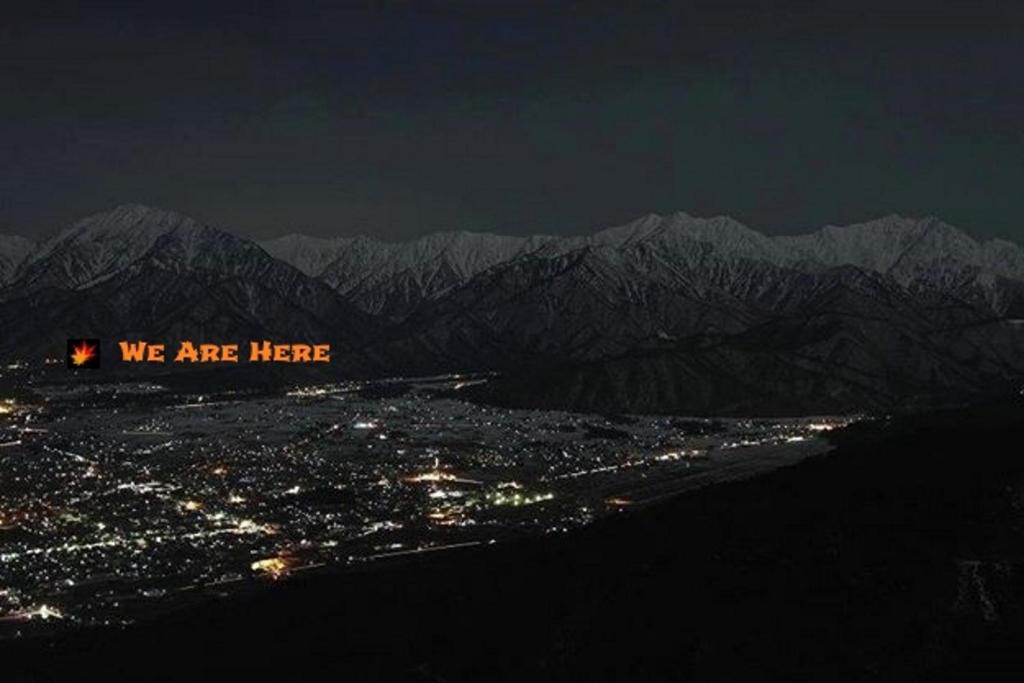 - une vue sur la ville et les montagnes la nuit dans l'établissement Momiji Guesthouse Cottages - Alpine Route, à Omachi