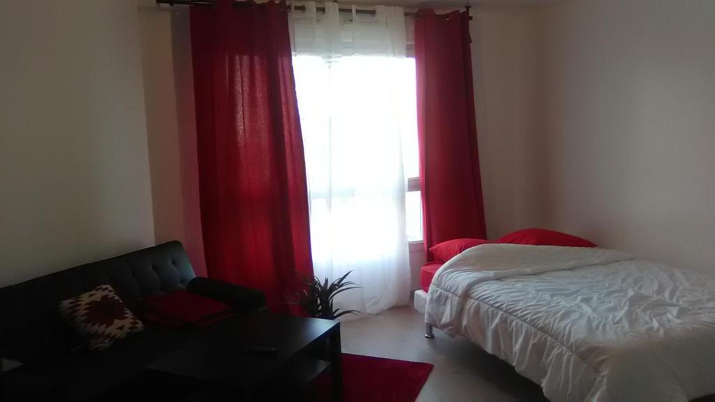 um quarto com uma cama e uma janela com cortinas vermelhas em Appartements Sully em Mantes-la-Jolie