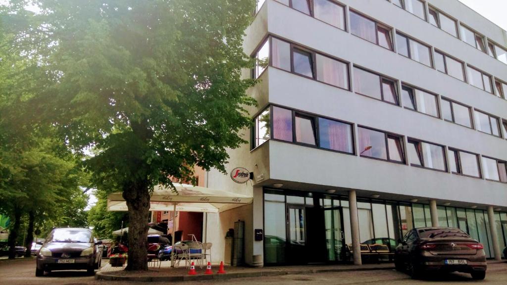 ein weißes Gebäude mit davor geparkt in der Unterkunft Carolina Hotel in Pärnu