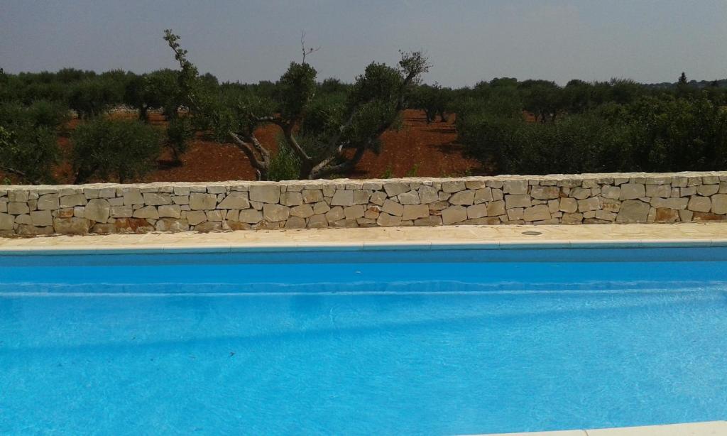 a stone retaining wall next to a swimming pool at Trullo La Canonica in Martina Franca