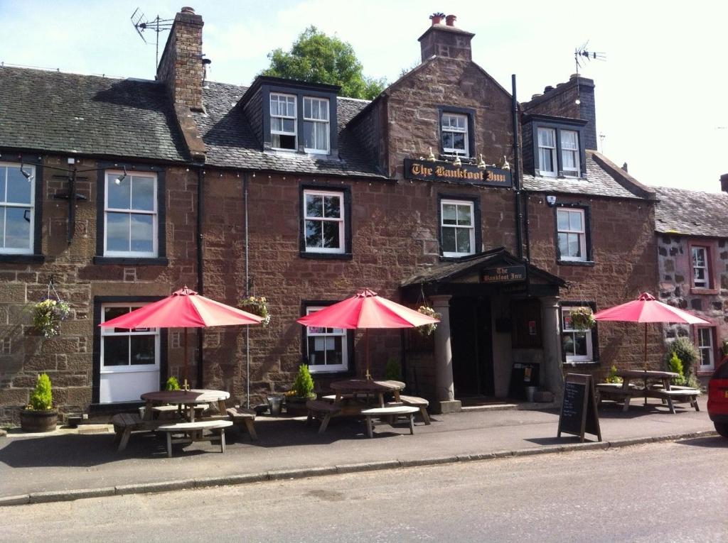 a building with tables and umbrellas in front of it at Bankfoot Inn in Bankfoot