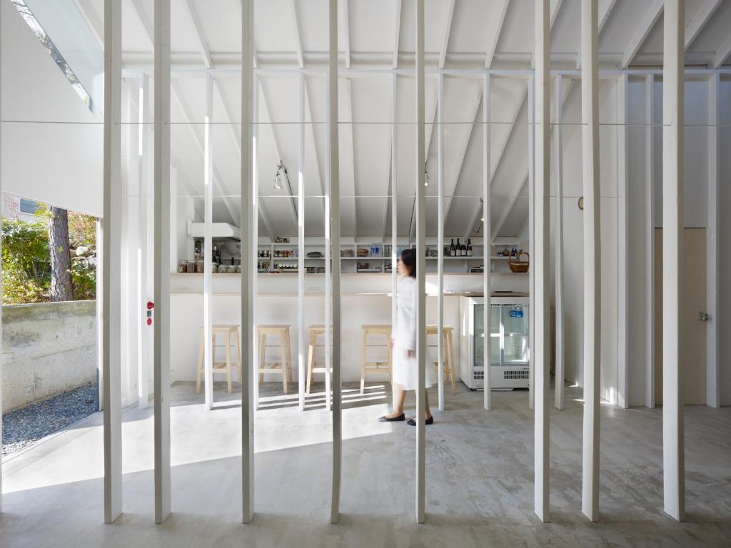 a woman is standing in a room with white columns at Koyasan Guesthouse Kokuu in Koyasan