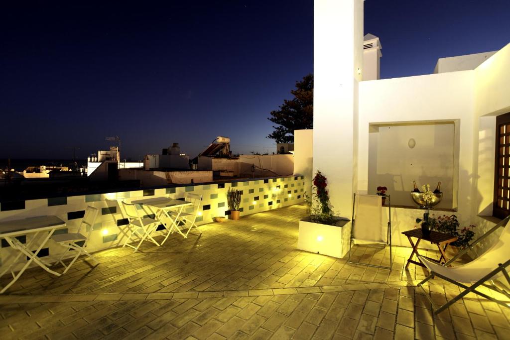 balkon z białymi krzesłami i stołami w budynku w obiekcie Hostal El Alojado de Velarde w mieście Conil de la Frontera