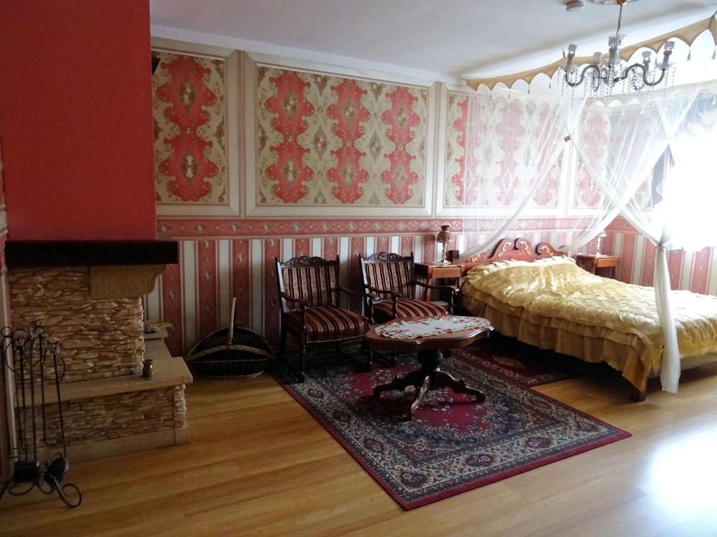 a bedroom with a bed and chairs and a fireplace at Agroturystyka Zacisze in Osowia