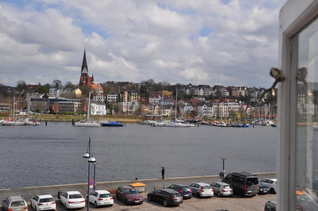 um grupo de carros estacionados ao lado de uma massa de água em Hafenblick vom Kapitänshaus em Flensburg