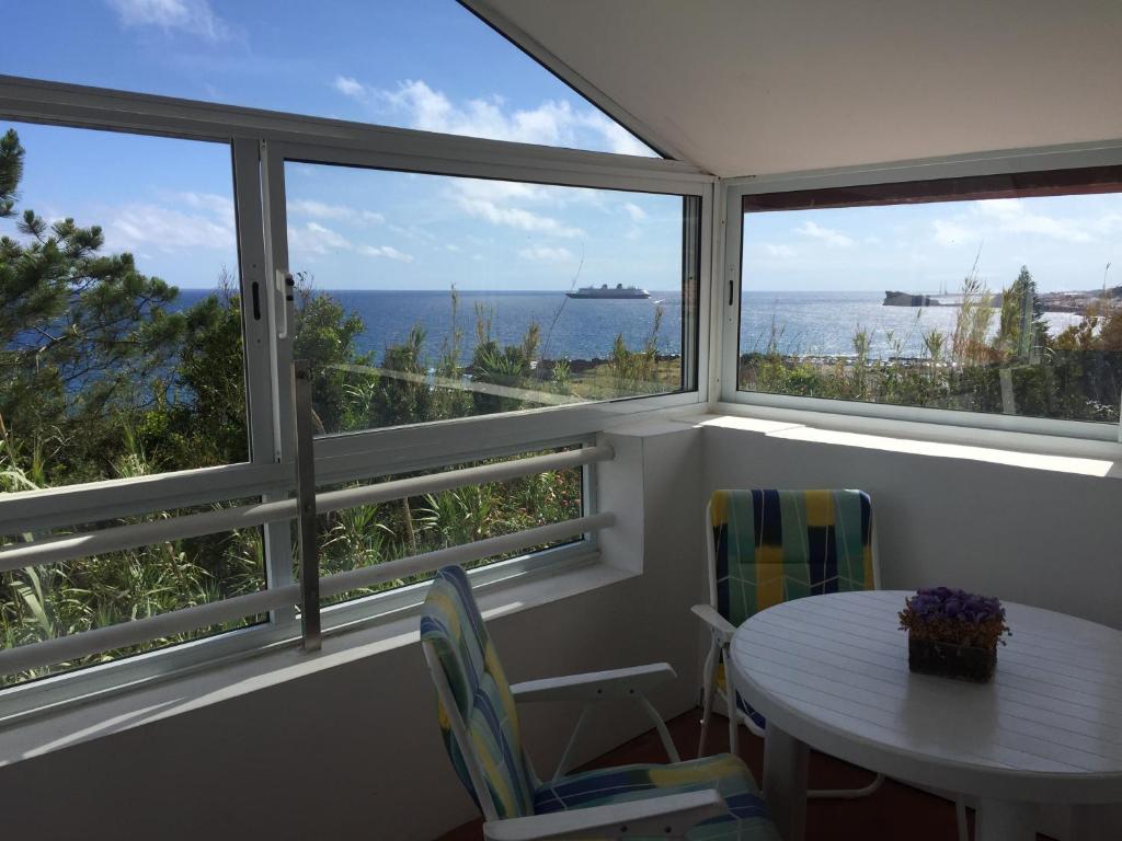 ポンタ・デルガダにあるPopulo Beach Atticのテーブルと椅子2脚、窓が備わる客室です。