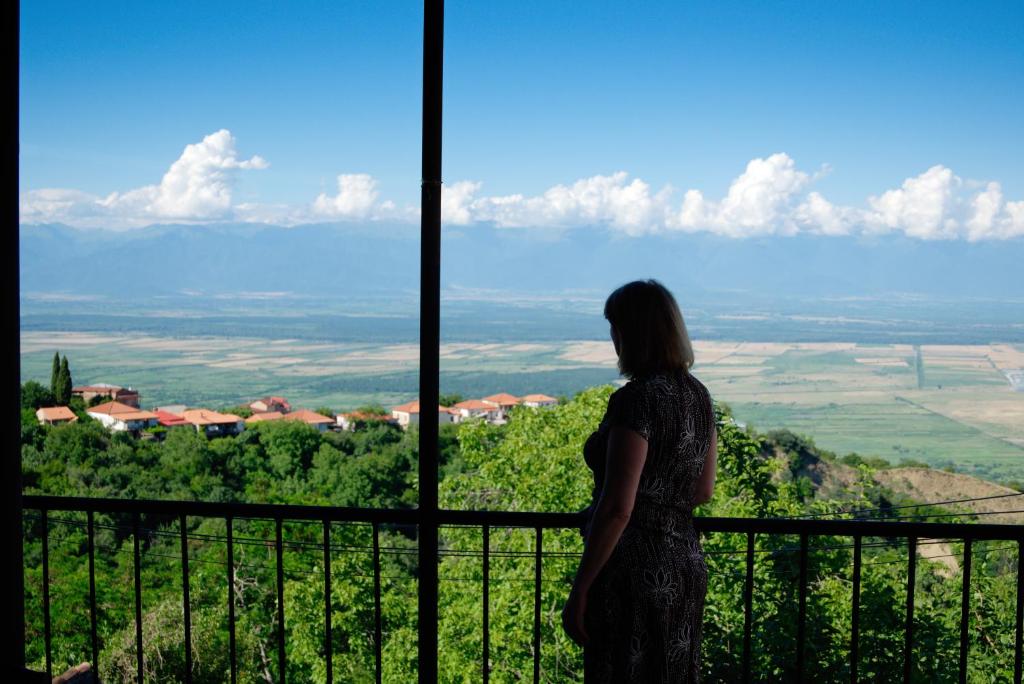 Una mujer parada en un balcón con vistas en Guest House Aisi, en Signagi