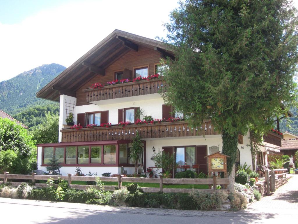 a house in the mountains with flowers on the balcony at Gästehaus Pöppl in Unterwössen