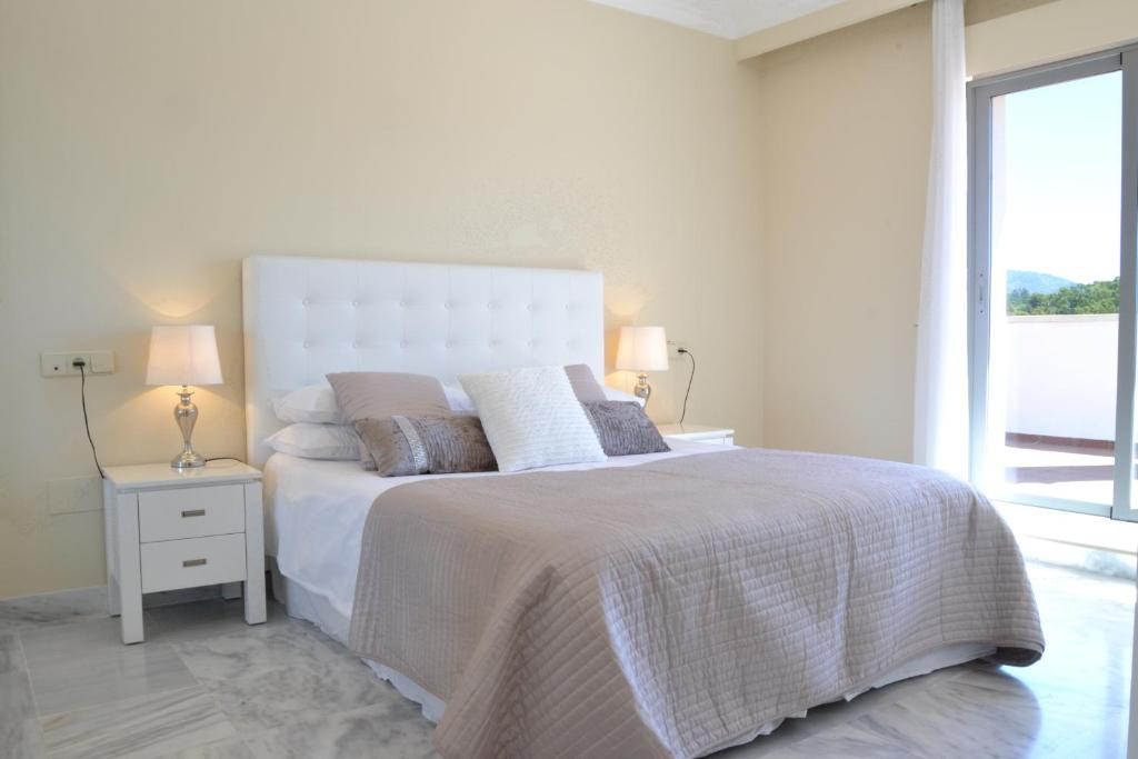マルベーリャにあるDama de Noche Penthouse RDR110の白いベッドルーム(大型ベッド1台、窓付)