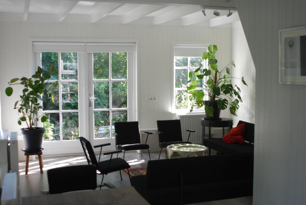 a living room with chairs and a couch and windows at Gina's garden house in Amsterdam