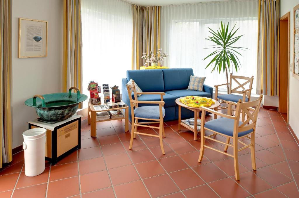 キュールングスボルンにあるBSW-Ferienwohnungen Kühlungsbornのリビングルーム(青いソファ、椅子、テーブル付)