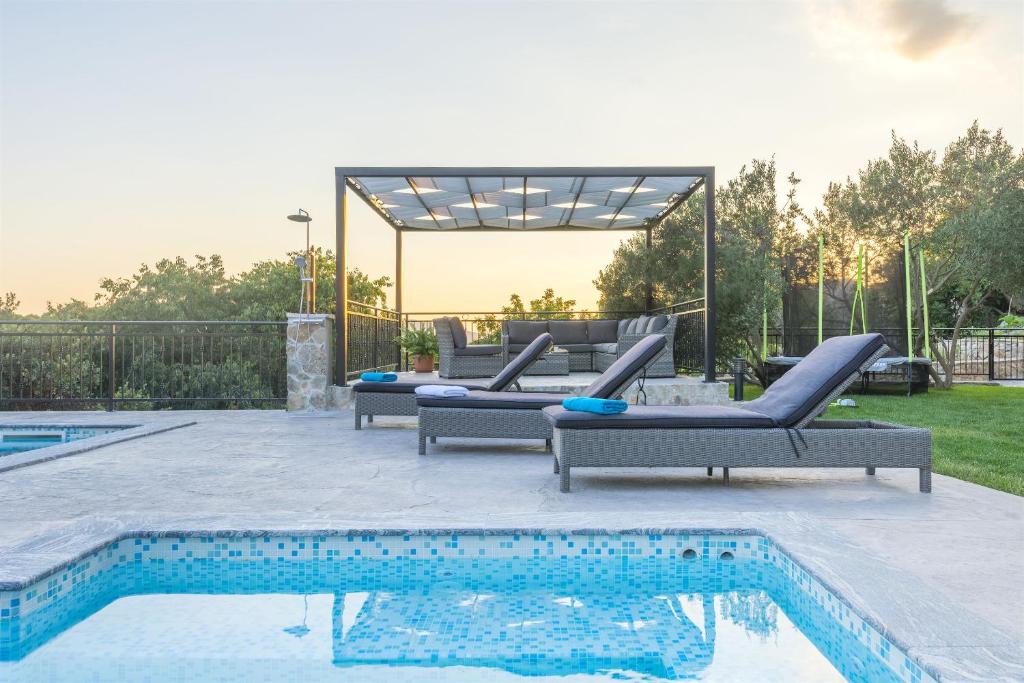 a pool with two lounge chairs next to a swimming pool at Villa Boulder in Okrug Donji