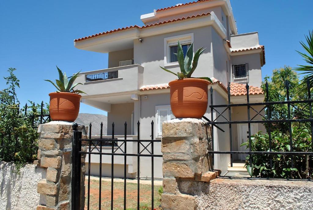 une maison avec trois plantes en pot sur une clôture dans l'établissement Angelina's Home, à Palaia Fokaia
