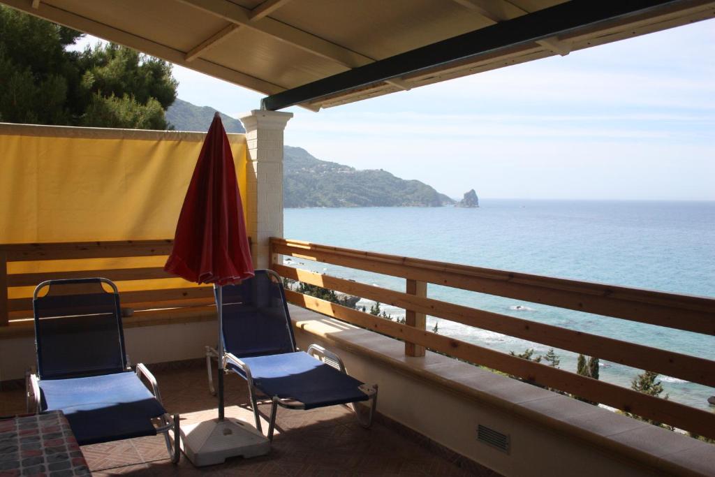 2 Stühle und ein Sonnenschirm auf einem Balkon mit Blick auf das Wasser in der Unterkunft Villa Gianitsi in Agios Gordios