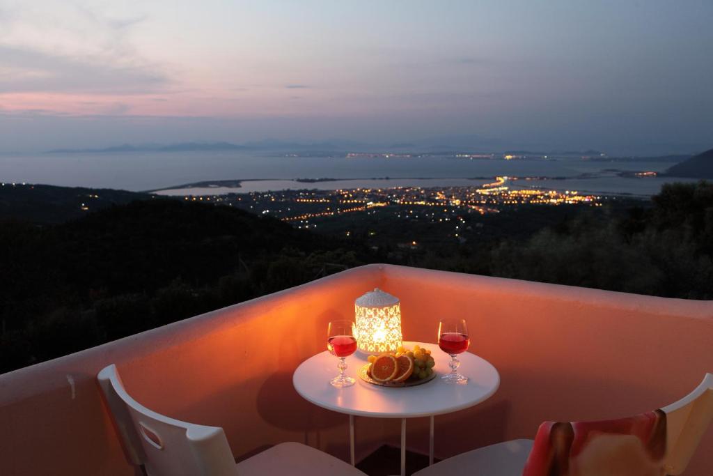 a table with two glasses of wine on a balcony at AmElia Villa in Spanokhórion