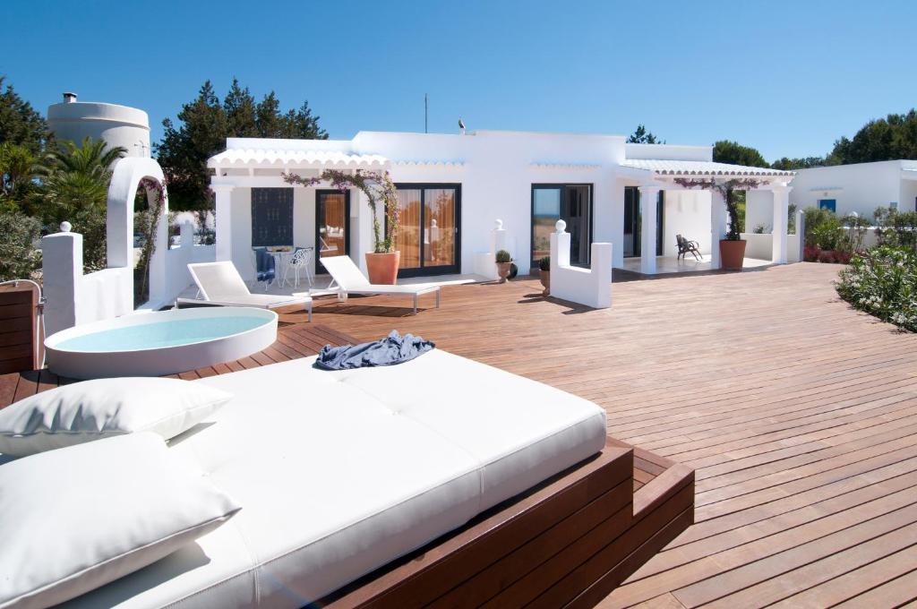 uma cama branca num deque de madeira em frente a uma casa em Villas Paraíso de los Pinos em Sant Francesc Xavier