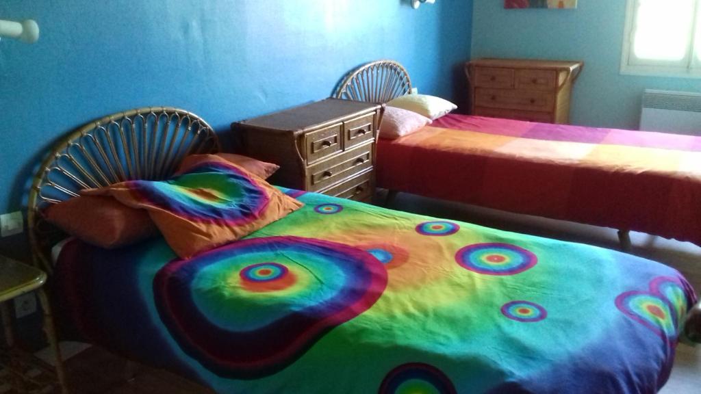a bedroom with two beds with a colorful blanket at La Grange in Le Plan