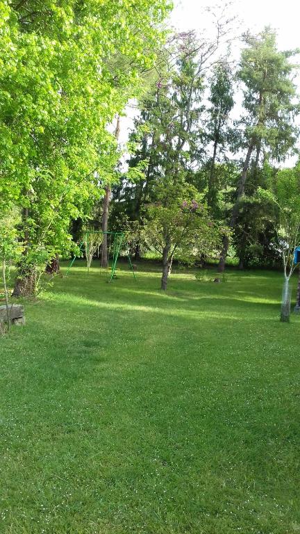 a park with trees and a swing set in the grass at La Grange in Le Plan