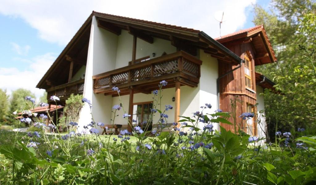 ein Haus mit Balkon auf einem Blumenfeld in der Unterkunft Ferienhäuser "In der Waldperle" in Bischofsmais
