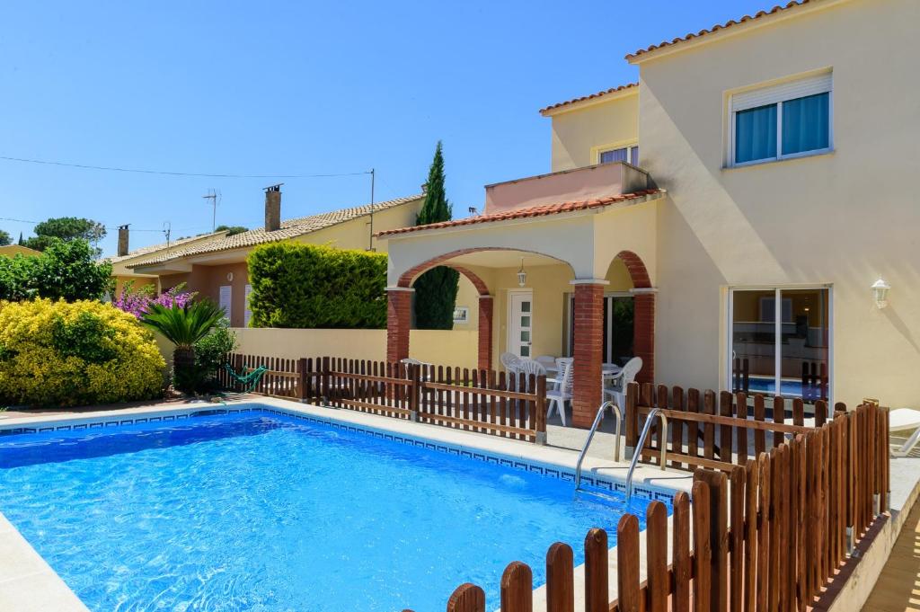 a villa with a swimming pool in front of a house at Costabravaforrent Ricardell in L'Escala