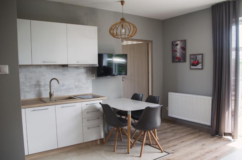 a kitchen with white cabinets and a table and chairs at Apartament Przystań in Darłowo
