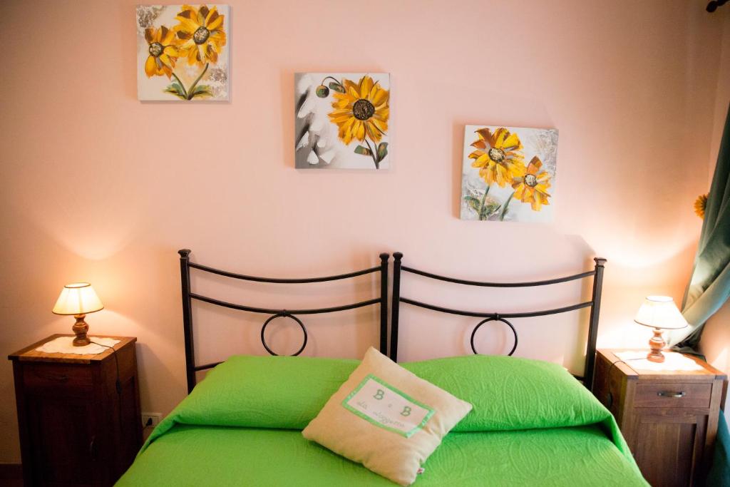 a bedroom with a green bed with paintings on the wall at La Loggetta in Bagnoregio