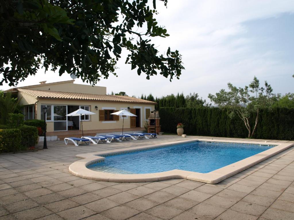 a swimming pool with chairs and a house at Can La Villa in Pollença
