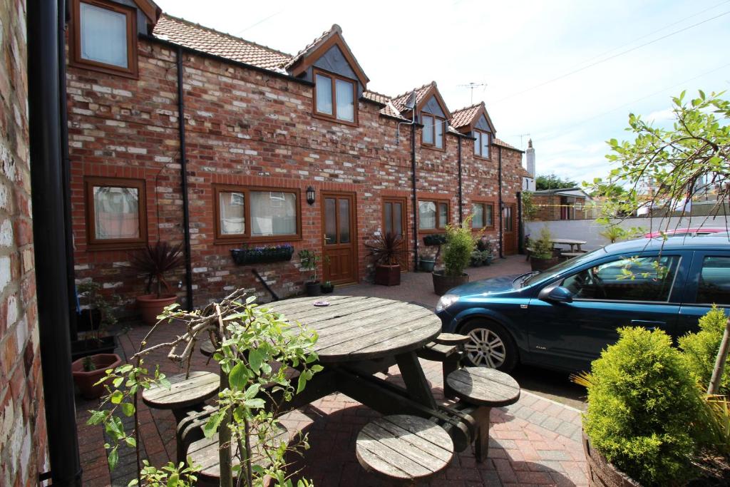 una mesa de picnic frente a un edificio de ladrillo con coche en Albion Cottages en Bridlington