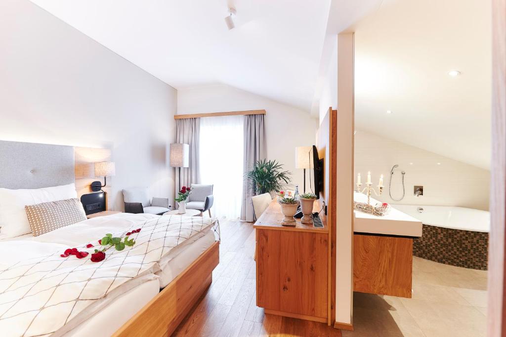 a hotel room with a bed and a bath tub at Landgasthaus Helpfauer Hof in Uttendorf