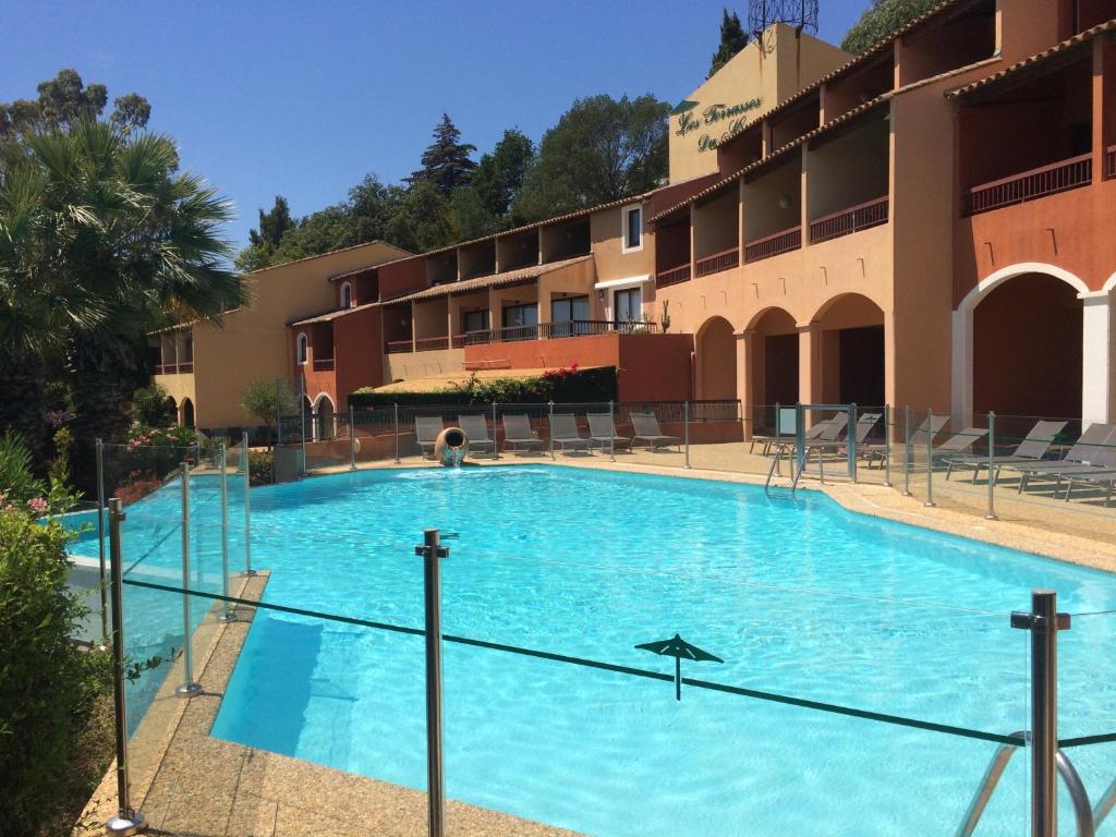 une grande piscine bleue en face d'un bâtiment dans l'établissement Les Terrasses, à Bormes-les-Mimosas